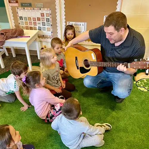Parent playing guitar for children